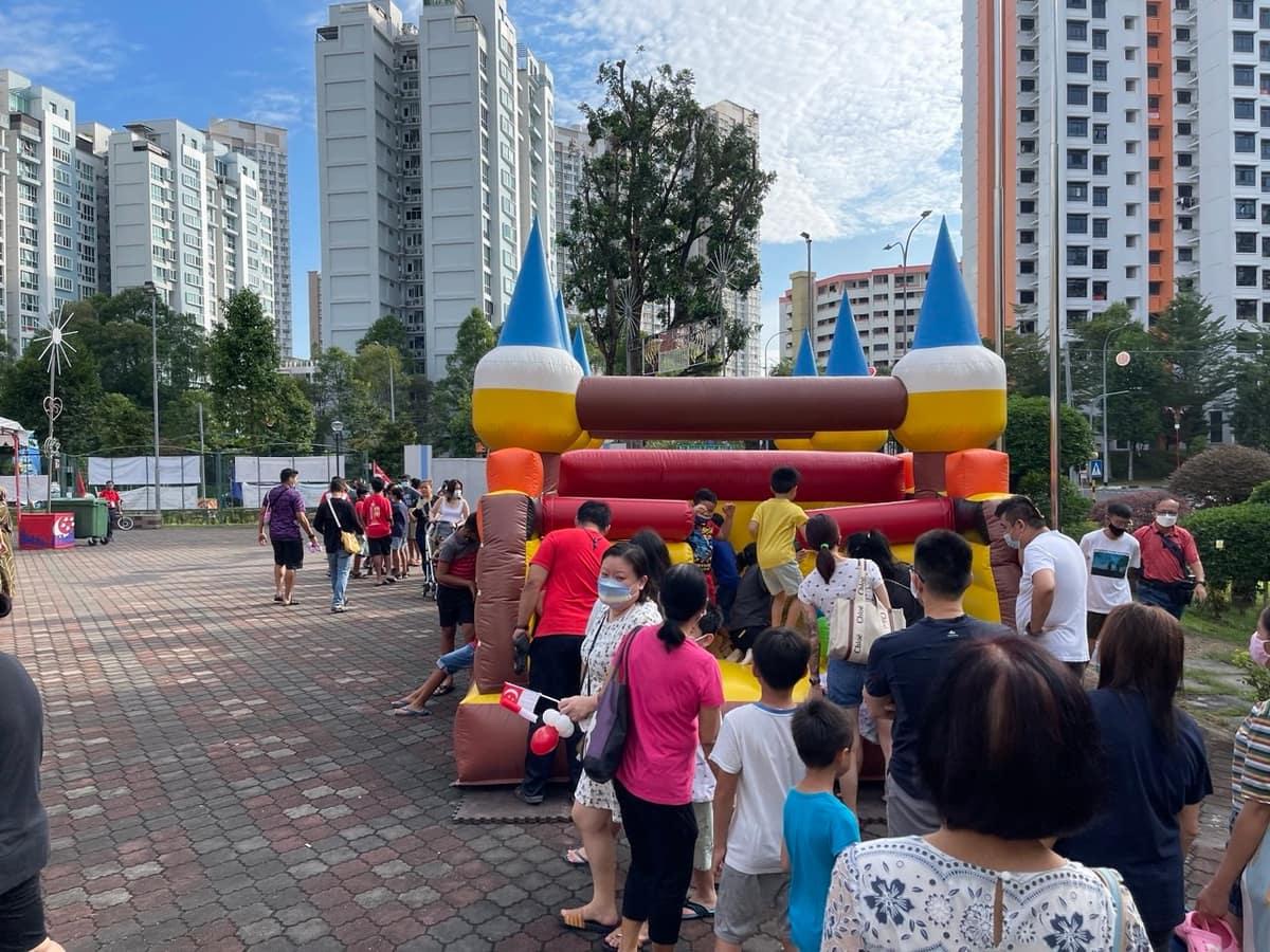 Large crowd around a bouncy castle in a plaza