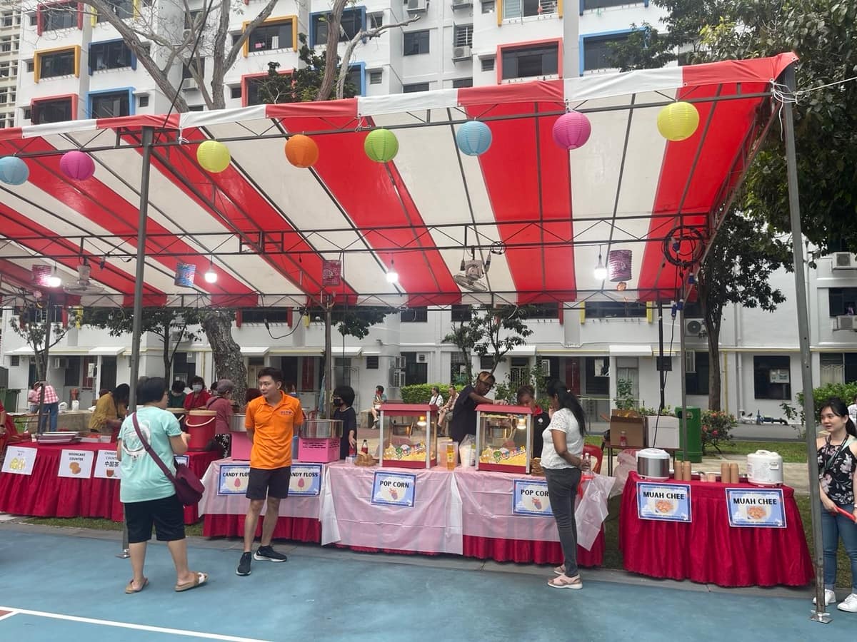 Wide view of a multi-stall carnival tent in an HDB estate